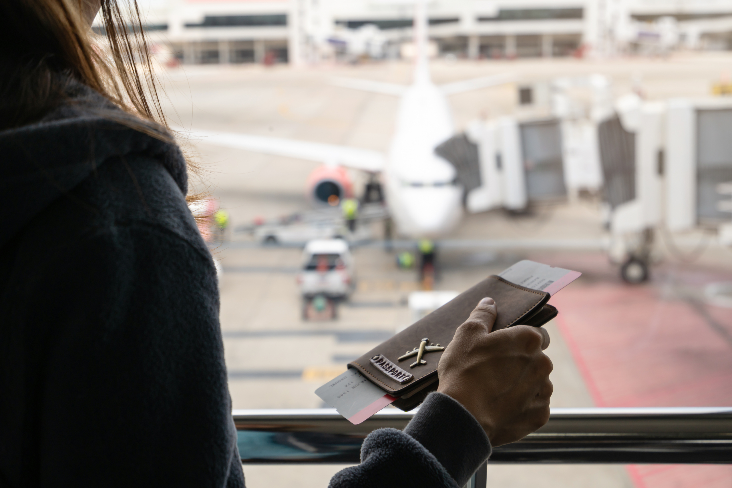 Young Woman Traveler With Luggage Holding Passport Looking At The Airplan